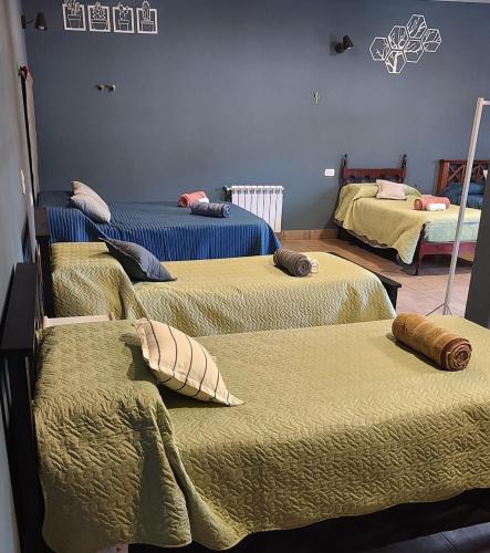a room with three beds with green blankets and pillows at Raíces Hospedaje in Humahuaca