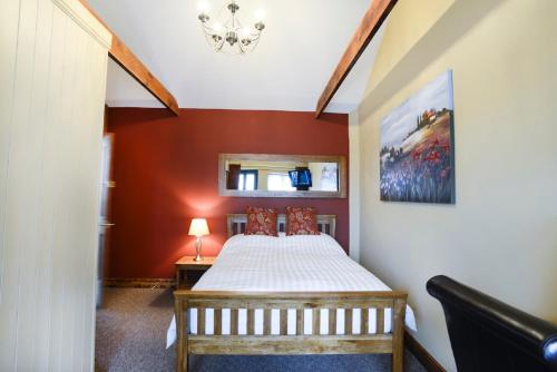 a bedroom with a bed and a red wall at Old Field Barn Luxury B & B in Attleborough