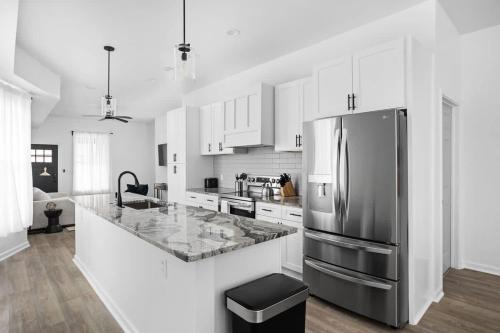 a kitchen with a stainless steel refrigerator and white cabinets at Full Duplex Retreat-Two Homes Near Eastside- Family Friendly in Indianapolis