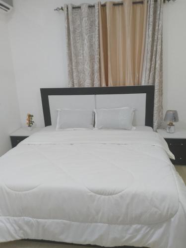 una cama blanca con sábanas y almohadas blancas en Carlo Van Apartment, en Accra