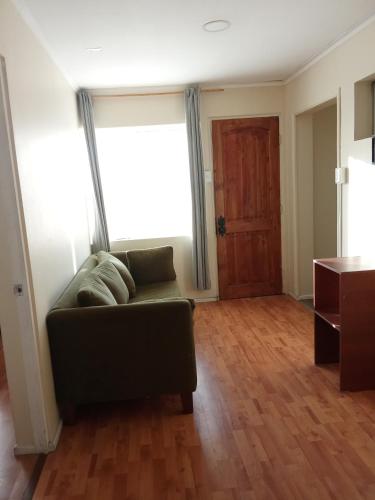 a living room with a couch and a large window at Cómodo y económico departamento en segundo piso in La Serena