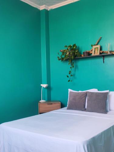 グアヤキルにあるHotel Pachamaの緑の壁のベッドルーム1室(白いベッド1台付)