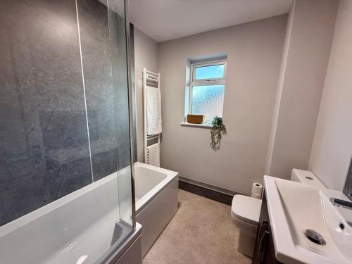 a bathroom with a tub and a sink and a toilet at Squires House Long Stays Sleep 10 Free Parking 