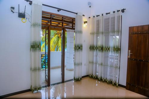 a room with transparent curtains and a door at Samasta Inn in Weligama