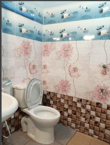 a bathroom with a toilet and flowers on the wall at Princess Villa Kandy Rail Station in Kandy