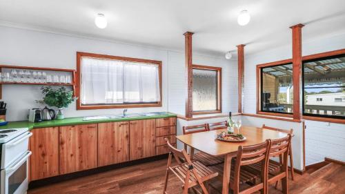 a kitchen with a wooden table and chairs and a counter at King Stingray in Currarong