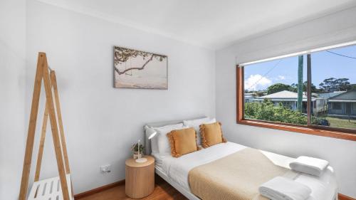 a white bedroom with a bed and a window at King Stingray in Currarong