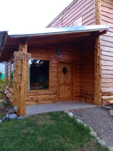 eine Holzhütte mit einer Tür und einer Veranda in der Unterkunft Cabaña La Delfina in Epuyén