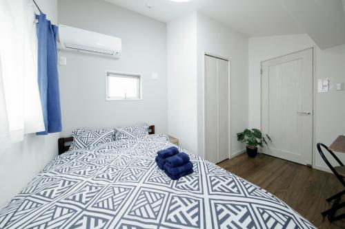 ein Schlafzimmer mit einem Bett und einem blauen Stuhl darauf in der Unterkunft Higashi Rokugou WHITE / Vacation STAY 4276 in Tokio