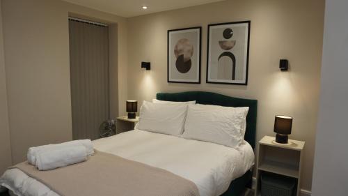 a bedroom with a bed with white sheets and two lamps at Cosy Leeds City Centre Apartment in Central Station