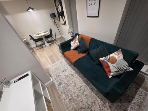 a living room with a green couch with pillows at Cosy Leeds City Centre Apartment in Central Station