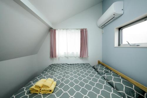 Bett in einem kleinen Zimmer mit Fenster in der Unterkunft HigashirokugoBLACK / Vacation STAY 4280 in Tokio