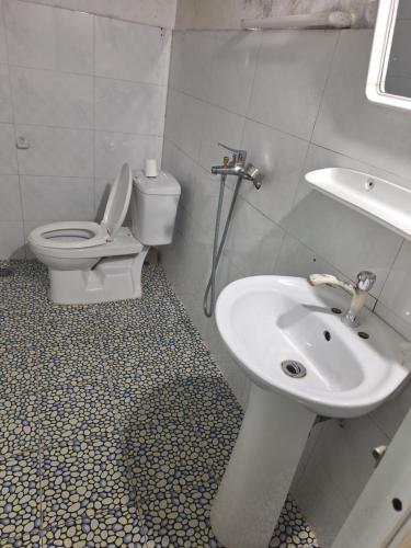 a white bathroom with a toilet and a sink at Sapa Tatu Homestay in Sapa