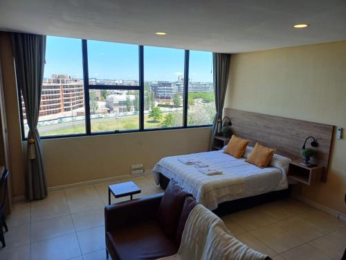 a bedroom with a bed and a couch and large windows at Apart , Departamento , Condo , Estudio BAHIA grande Nordelta , Tigre in Buenos Aires