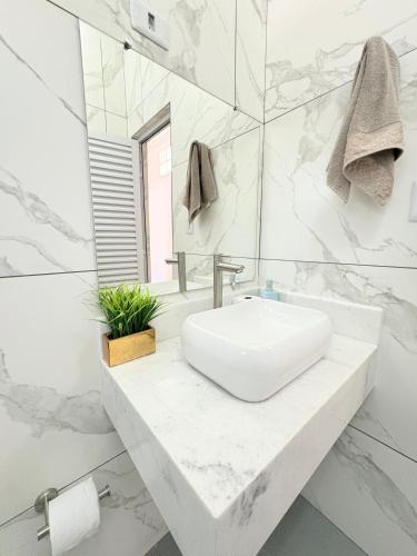 a white bathroom with a sink and a mirror at CASA ACONCHEGANTE e PERTINHO DA PRAIA in Bertioga