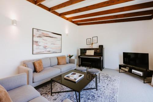 a living room with a couch and a piano at 8th Tee - Retro Vibes Peacefully Tucked Away in Mudgee
