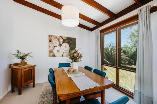 a dining room with a table and chairs and a window at 8th Tee - Retro Vibes Peacefully Tucked Away in Mudgee