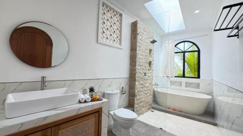 a bathroom with a tub and a toilet and a sink at Candra Villa Kedungu in Tanah Lot