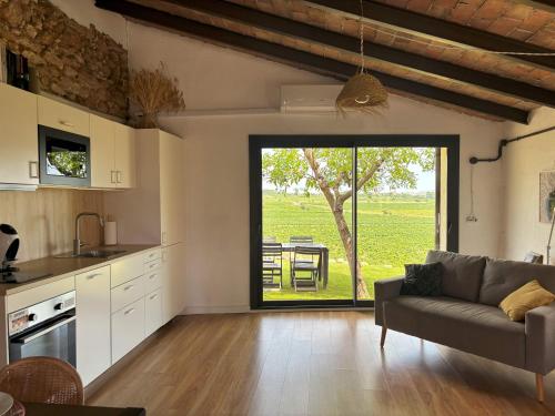 a living room with a couch and a large window at Cabernet Rural in Sant Jaume dels Domenys