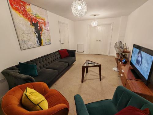a living room with a couch and a flat screen tv at Garland Modern 4 Bedroom House with Garden & Parking in Kent