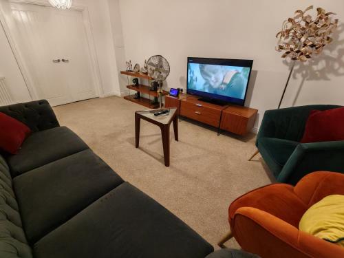 a living room with a couch and a tv at Garland Modern 4 Bedroom House with Garden & Parking in Kent