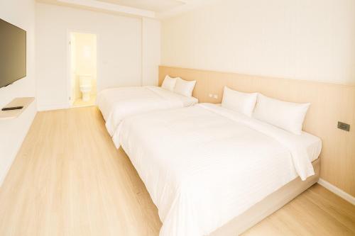 Habitación con 2 camas, paredes blancas y suelo de madera. en Xing Yu Hotel, en Mao-i-san-ts'un