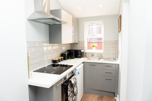 a white kitchen with a sink and a stove at Rb Lodge Stockport in Stockport