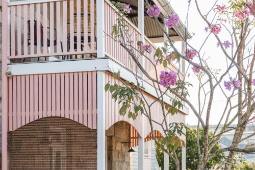ブリスベンにあるMiss Midgley's - Refectoryの門と花のあるピンクと白の建物