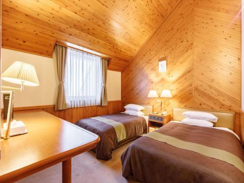 two beds in a room with wooden walls at Kibi Kogen Resort Hotel in Kaga