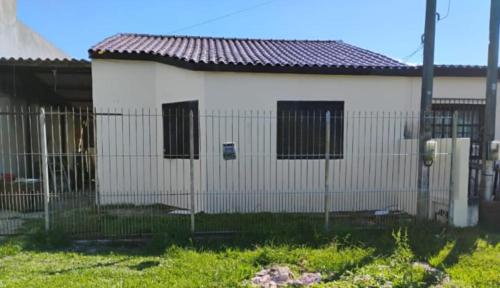 a white building with a fence in front of it at Casa completa proximo a FURG in Rio Grande
