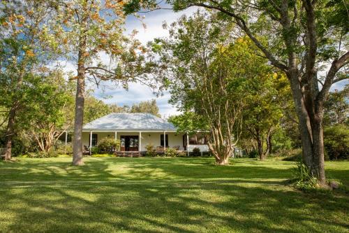 a white house with trees in the yard at Old Duninald House - Historic Farmhouse Experience in Paterson
