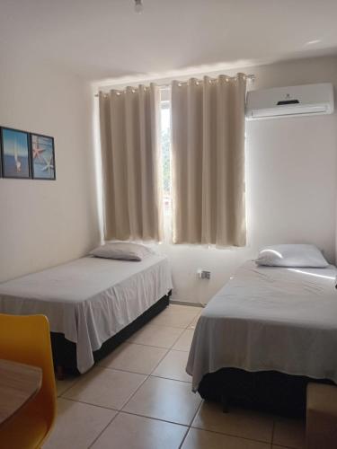 a room with two beds and a window at Apartamento próximo praia in Florianópolis