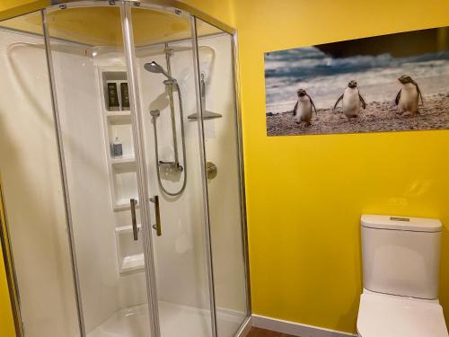 Un baño con ducha con tres pingüinos en la pared. en Oakhampton Lodge, en Kaiapoi