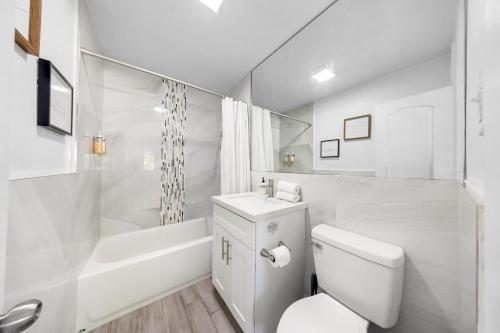 a white bathroom with a toilet and a bath tub at Spacious Fort Lauderdale Bungalow 10mins Airport & Beach Near Miami in Fort Lauderdale