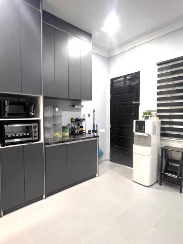a kitchen with black cabinets and a white refrigerator at CFD HOMESTAY PB Dungun Private Pool in Dungun