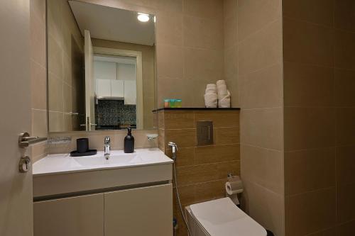 a bathroom with a sink and a toilet and a mirror at Masdar Modern Studio in Abu Dhabi