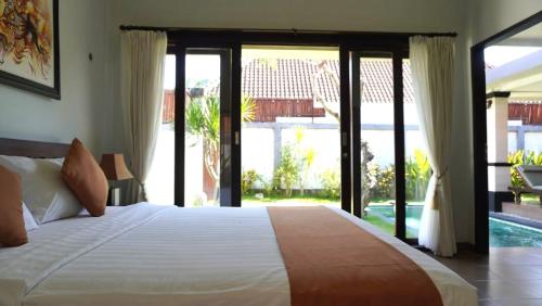 塞米亚克Tahoma Villas Seminyak by ABM的一间卧室设有一张大床和滑动玻璃门