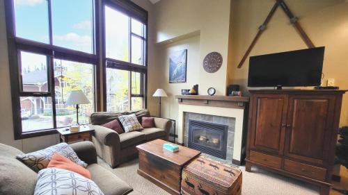 a living room with a television and a fireplace at Stones Throw #38 By Bear Country in Sun Peaks