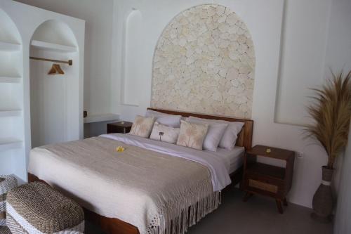 a bedroom with a large bed with white sheets and pillows at Momy Breeze Uluwatu in Bingin Beach