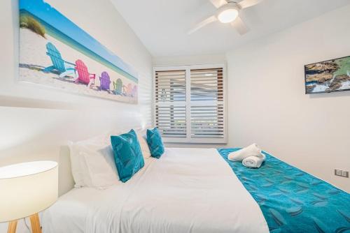 a bedroom with a large white bed with blue accents at Sea Esta - Lennox Head in Lennox Head