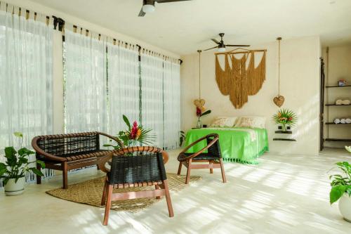 a living room with a green bed and chairs at Jungle Tiny Home Retreat - Casa de Seda in Chemuyil