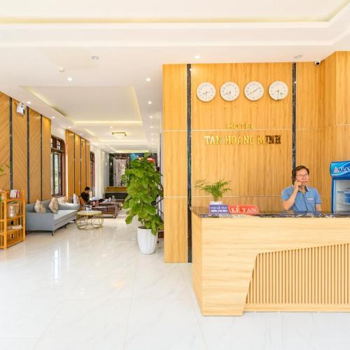 a person standing behind a counter in a lobby at Tan Hoang Minh Hotel in Dong Hoi