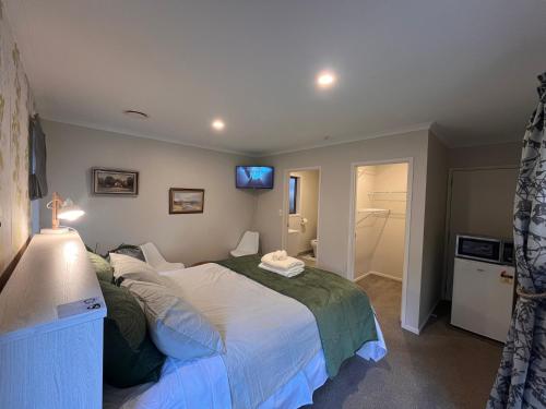 Hillpark Hideaway في أوكلاند: غرفة نوم بسرير وتلفزيون على الحائط