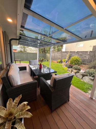 a patio with couches and a table on a deck at Hillpark Hideaway in Auckland