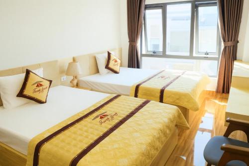 a hotel room with two beds and a desk at Thanh Tung Hotel in Ha Long