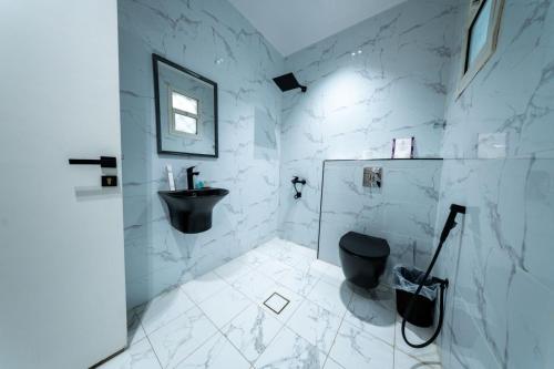 a bathroom with a black toilet and a sink at Ohud Suites - أجنحة أحد in Riyadh