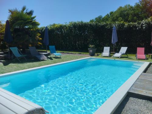 une piscine avec chaises et parasols dans l'établissement Domaine la belle charentaise, à Chadenac