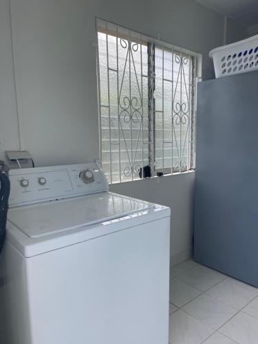 a kitchen with a washing machine and a refrigerator at Pams Lodge Barbados in Christ Church