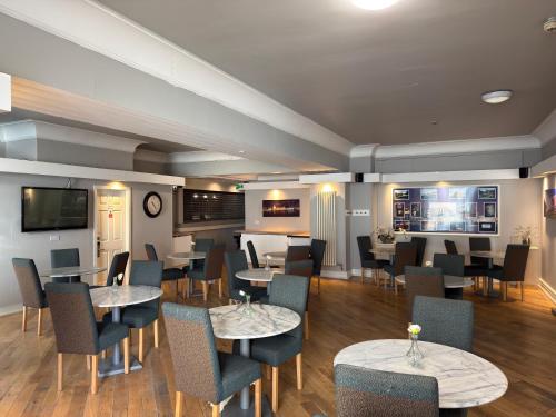 a restaurant with tables and chairs and a television at Lord Nelson Hotel-Lime Street Station Liverpool by Compass Hospitality in Liverpool