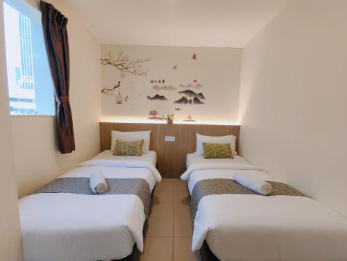 a row of three beds in a room at SCC Gateway Chinatown Hotel in Kuala Lumpur